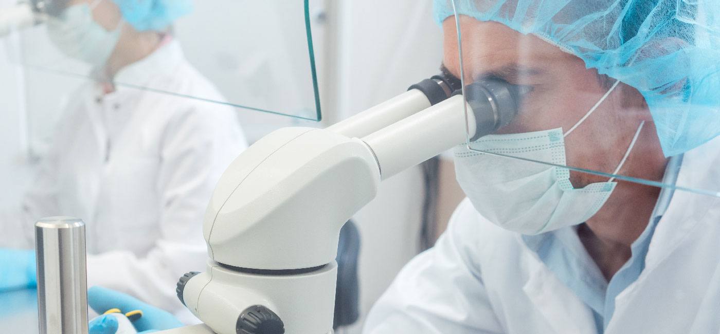 A scientist uses a microscope in a clinical setting